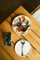 A rustic wooden table with dumplings arranged neatly alongside dipping sauces in elegant bowls.