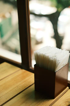 Elegant white linen napkins folded on a rustic wooden table with soft natural light