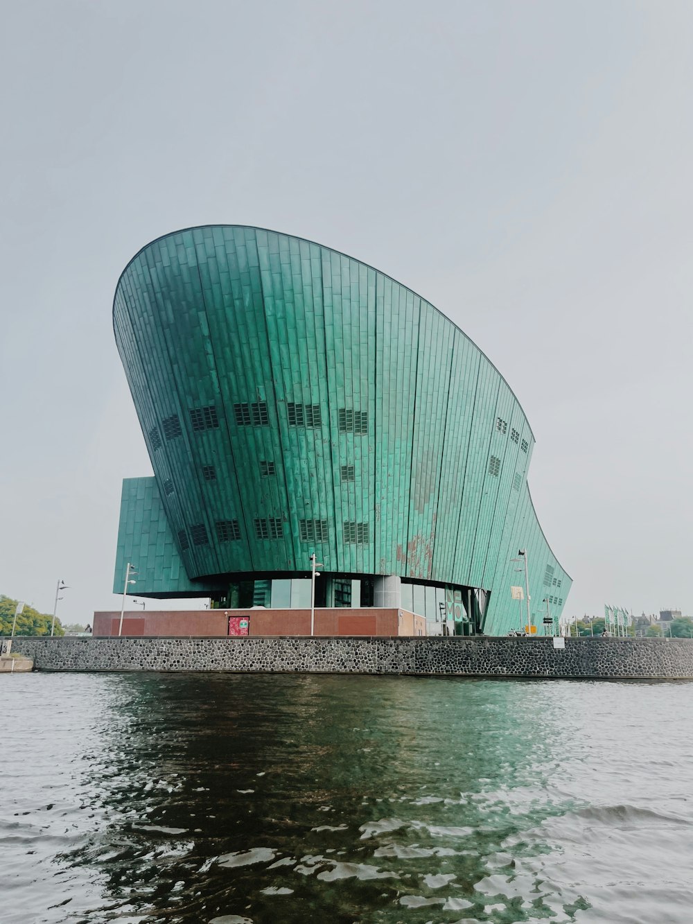 Un gran edificio verde sentado encima de un cuerpo de agua