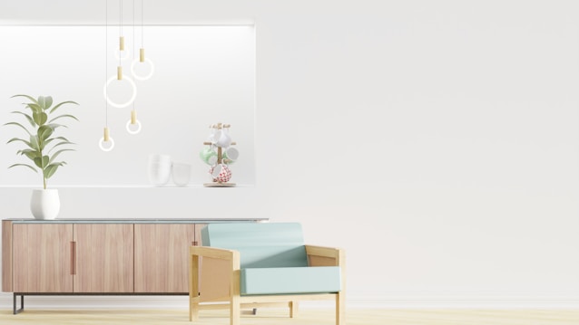 A minimalist interior design featuring a wooden sideboard with sleek lines and a potted plant on top. Modern pendant lights with circular designs hang from the ceiling, and decorative items are arranged on a recessed shelf. A light blue armchair with a wooden frame is positioned in the foreground, enhancing the contemporary aesthetic.