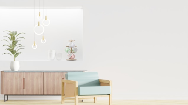 A minimalist interior design featuring a wooden sideboard with sleek lines and a potted plant on top. Modern pendant lights with circular designs hang from the ceiling, and decorative items are arranged on a recessed shelf. A light blue armchair with a wooden frame is positioned in the foreground, enhancing the contemporary aesthetic.