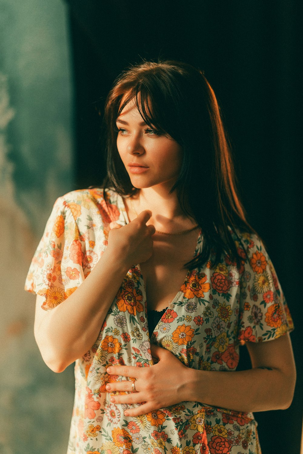 a woman standing in front of a wall with her hands on her chest