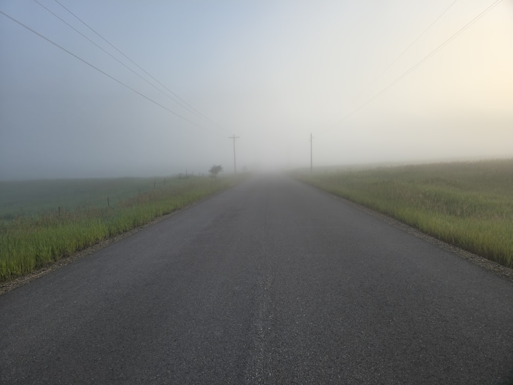 a foggy road with power lines in the distance