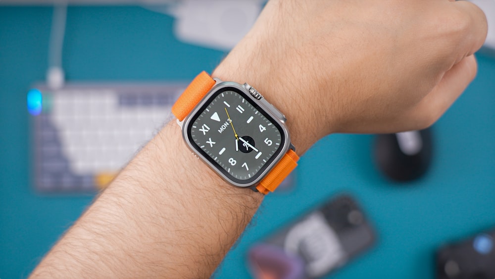 a man wearing an orange and silver apple watch