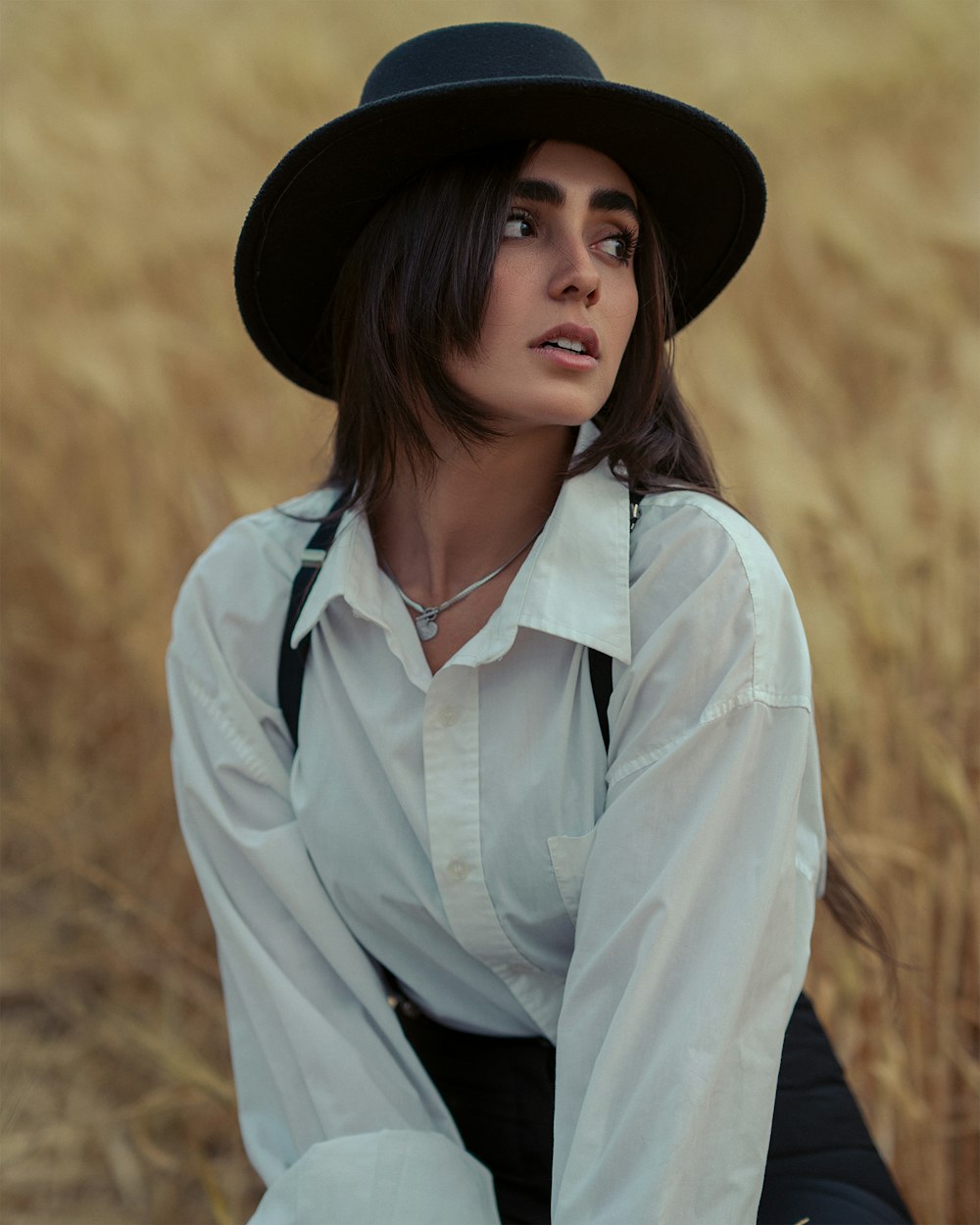 a woman in a hat is sitting in a field