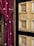 A rich red velvet curtain with embroidered floral patterns is elegantly draped beside a detailed wooden door featuring intricate geometric carvings. The door's natural wood tones are complemented by black accents framing the carved panels.