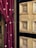 A rich red velvet curtain with embroidered floral patterns is elegantly draped beside a detailed wooden door featuring intricate geometric carvings. The door's natural wood tones are complemented by black accents framing the carved panels.