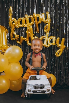 A smiling child celebrating a birthday with colorful balloons.