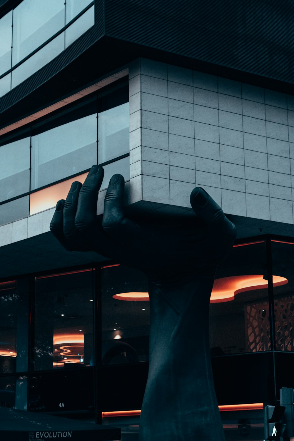 a statue of a hand holding a large object in front of a building