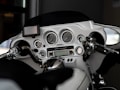The image displays the dashboard of a motorcycle, including a set of analog gauges, a small digital screen, and multiple control buttons. The handlebars and mirrors are visible, with chrome detailing and a sleek, modern design.