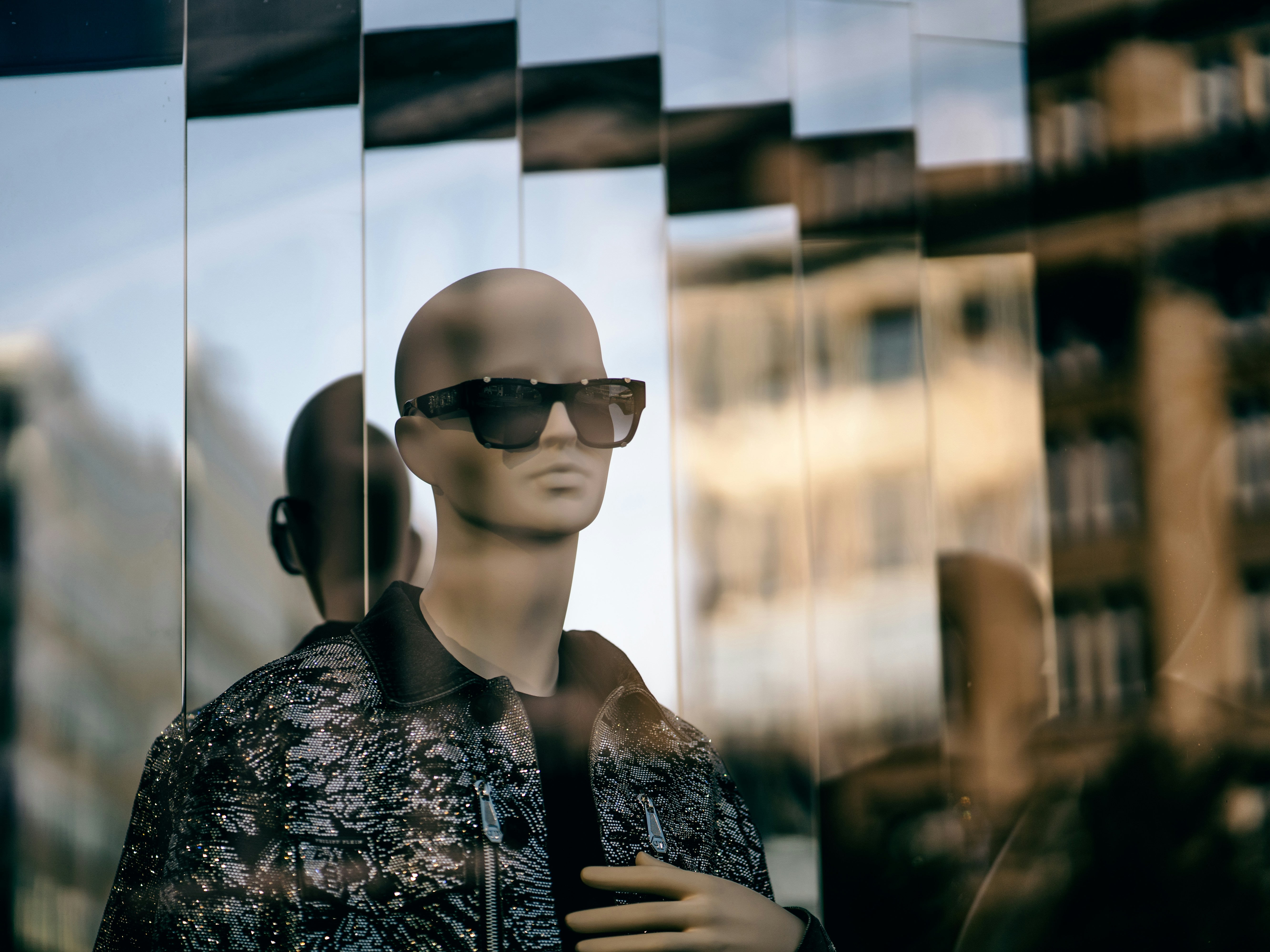 a mannequin wearing sunglasses in front of a window