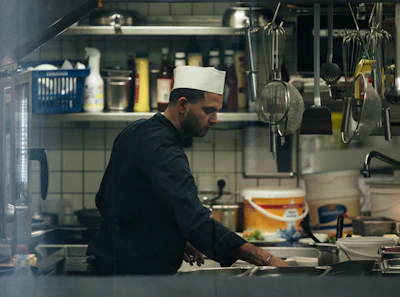 A chef using hygienic cleaning supplies in a busy restaurant kitchen.