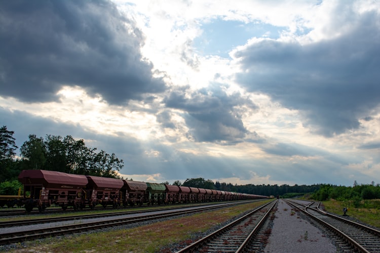a train traveling down train tracks under a cloudy sky
