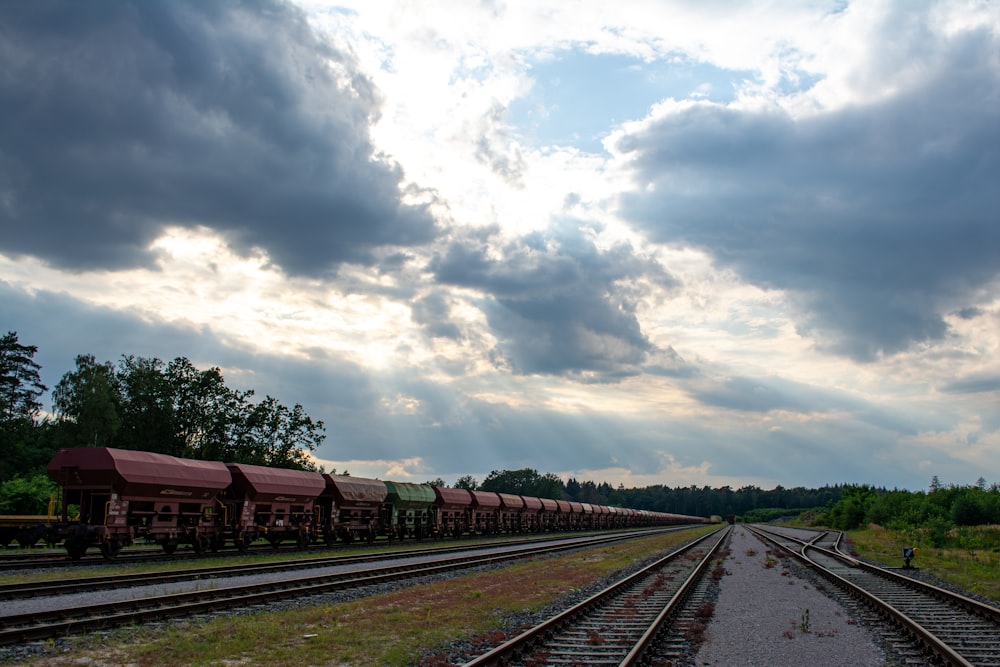 a train traveling down train tracks under a cloudy sky