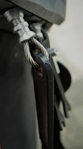 Close-up of a neatly coiled CNC machine cable with visible connectors on a dark industrial surface.