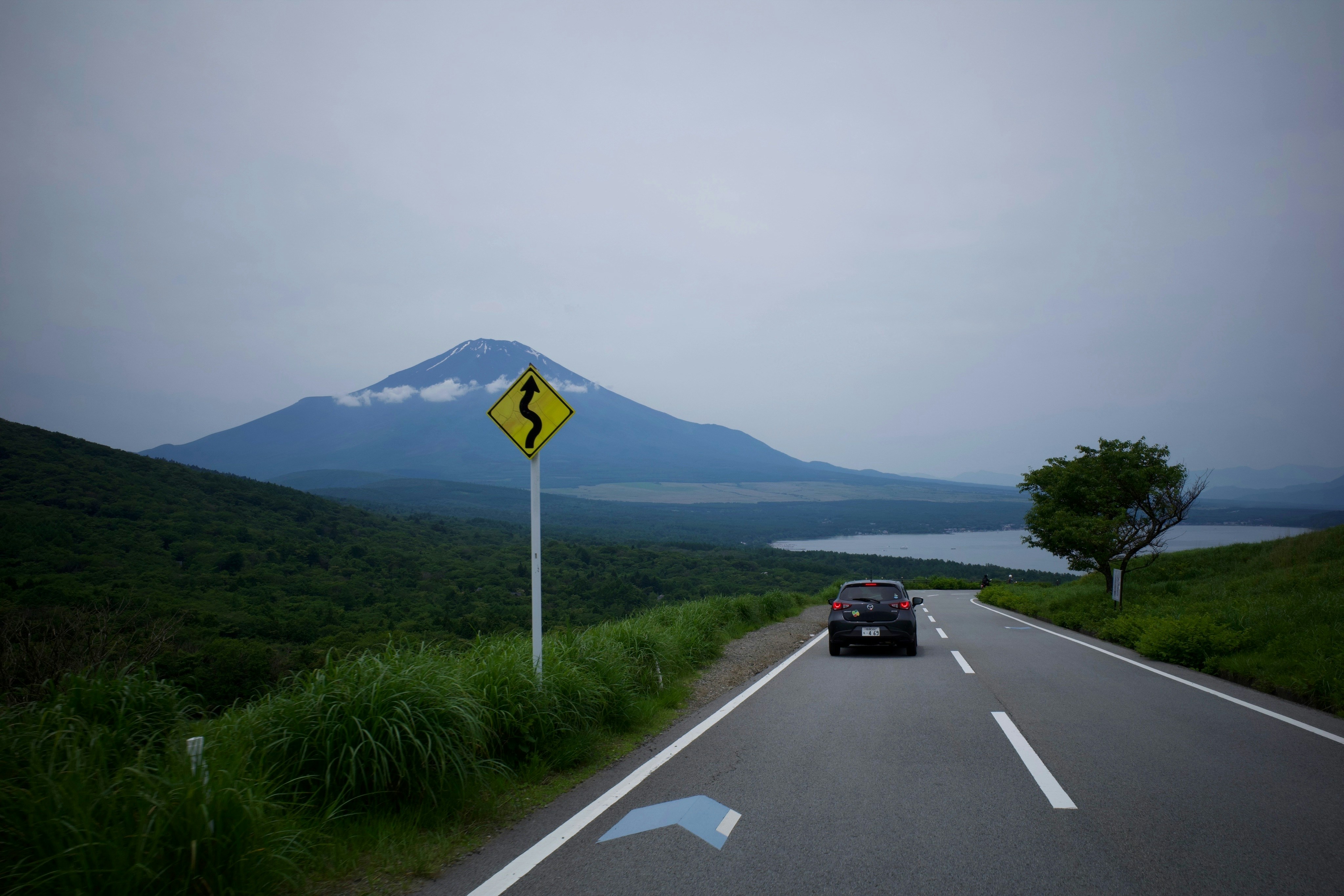a car driving down a road with a mountain in the background
