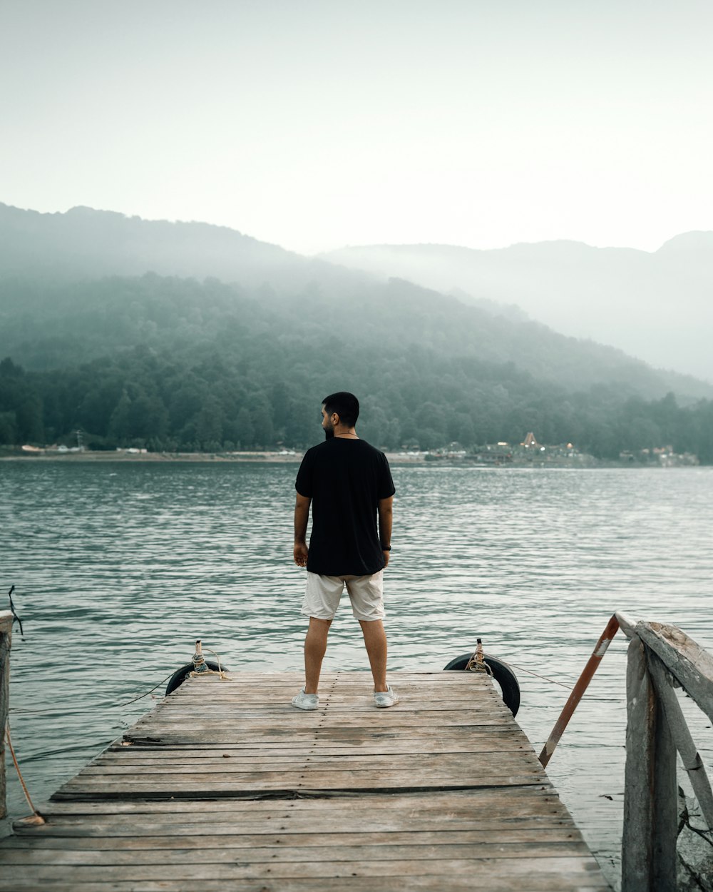a man standing on a dock looking at the water