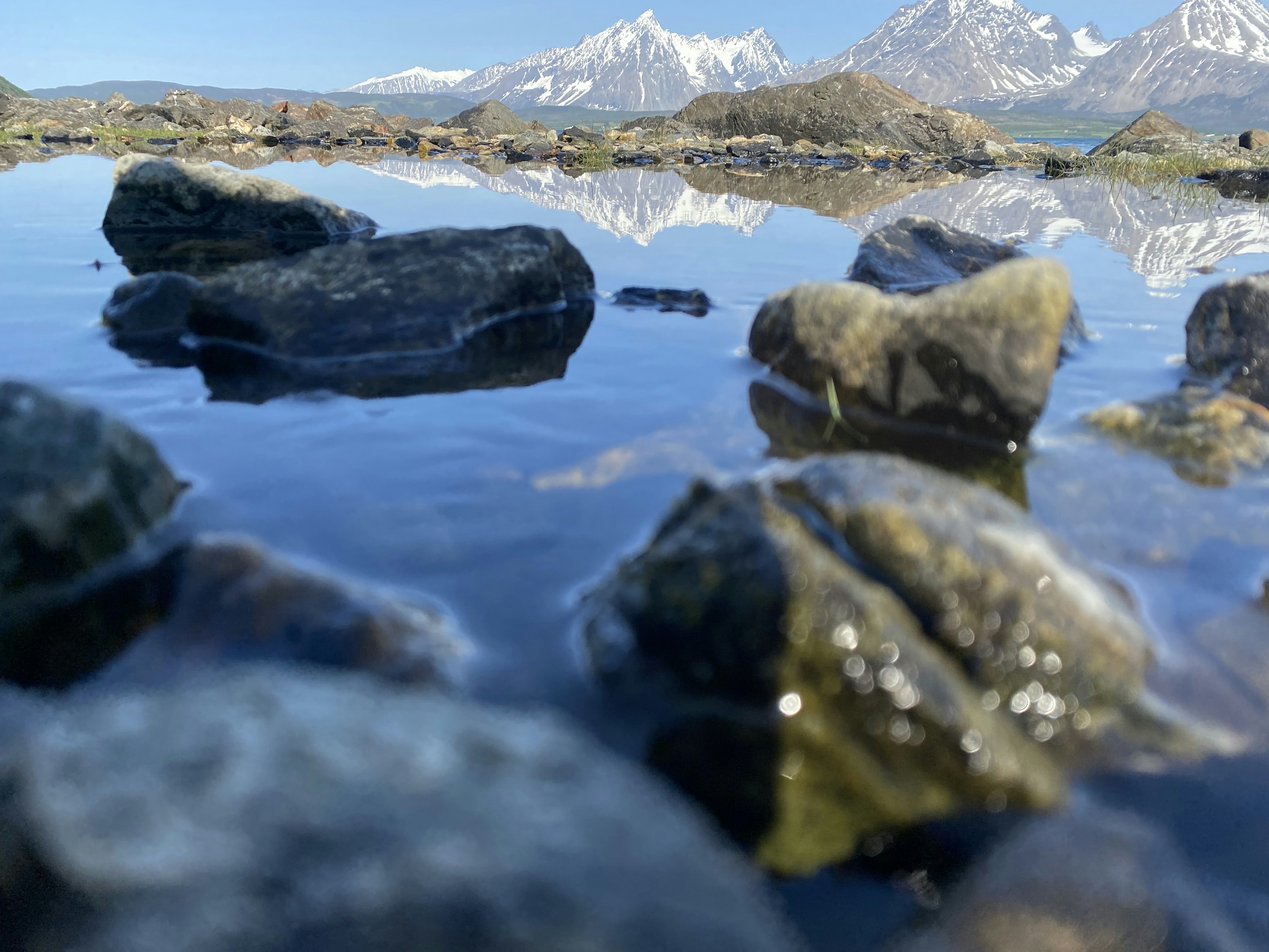 rocks in the water with mountains in the background