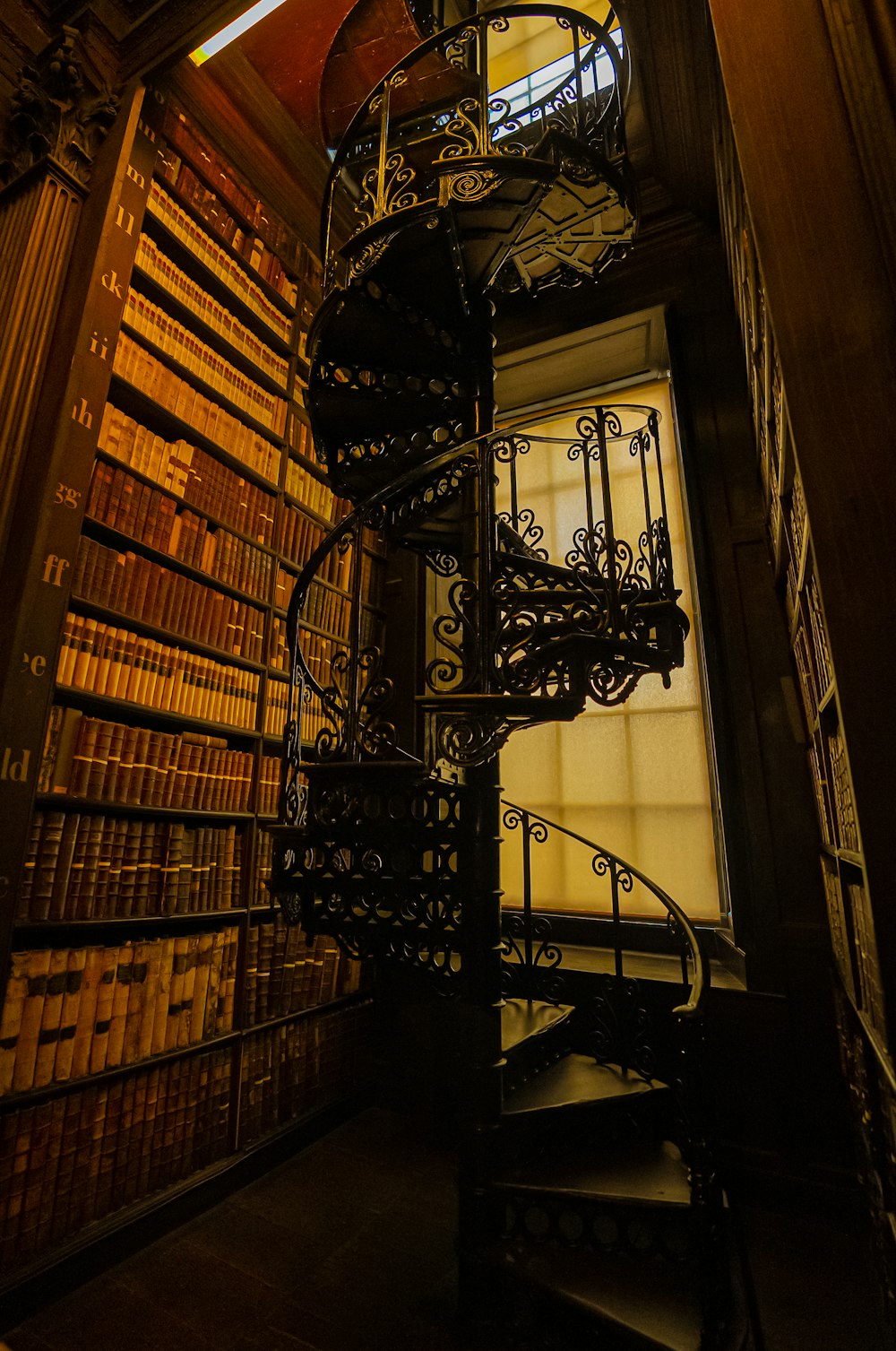 a spiral staircase in a library with lots of books