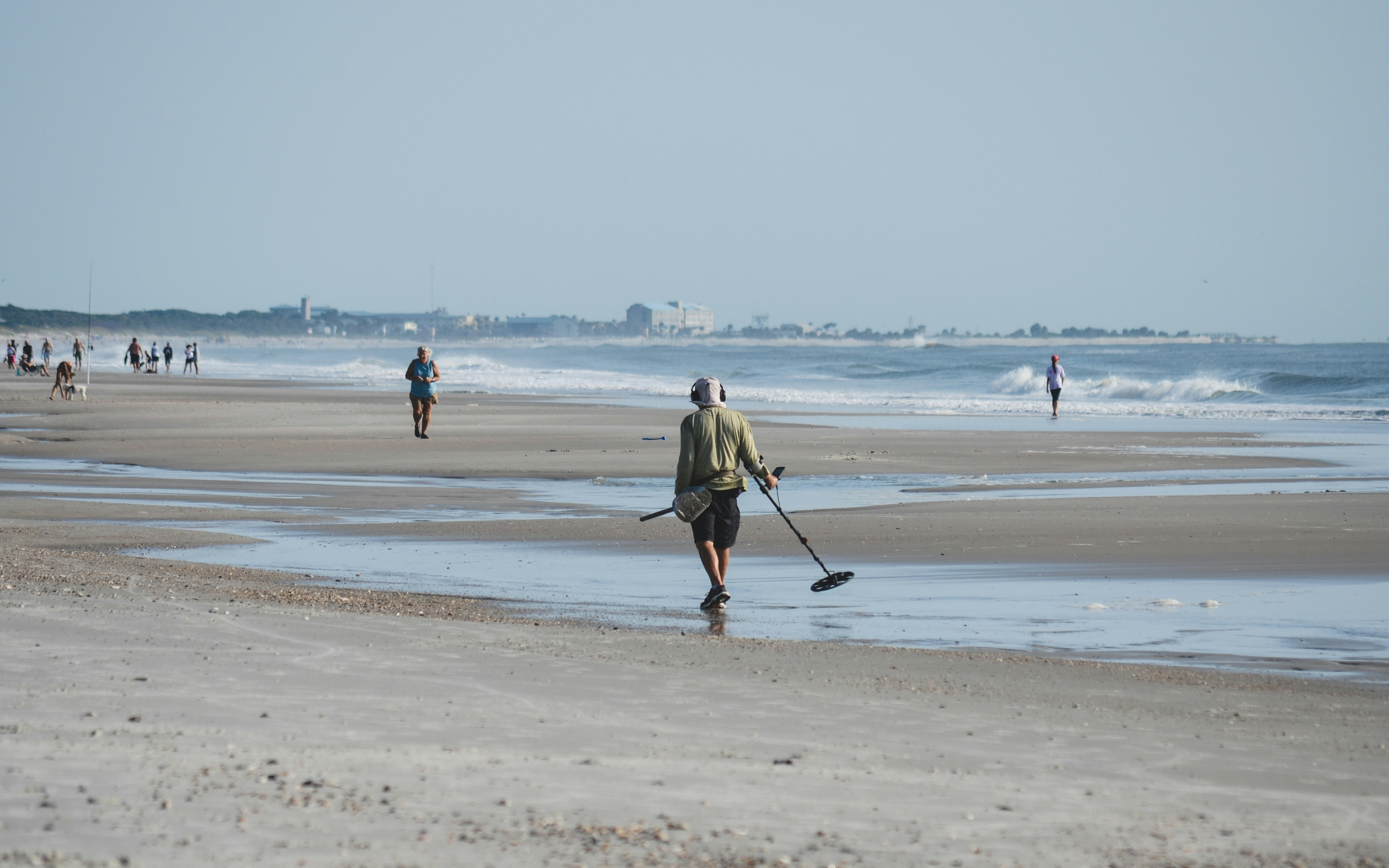 a man is walking on the beach with a stick