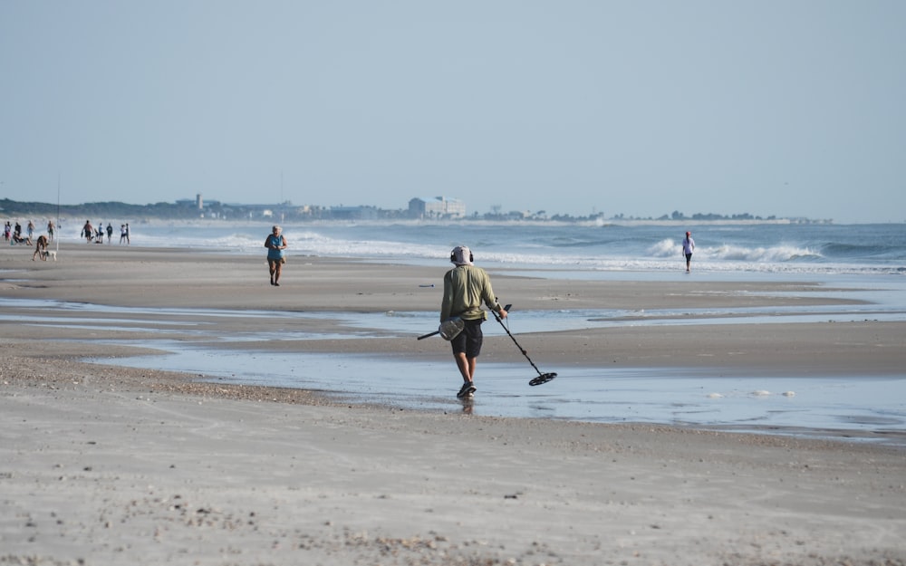 a man is walking on the beach with a stick