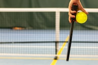 a person holding a tennis ball and a racket
