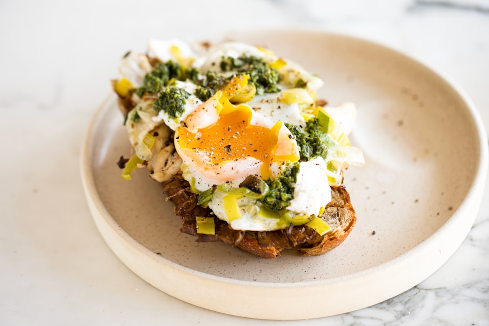 a white plate topped with a piece of toast covered in eggs and broccoli