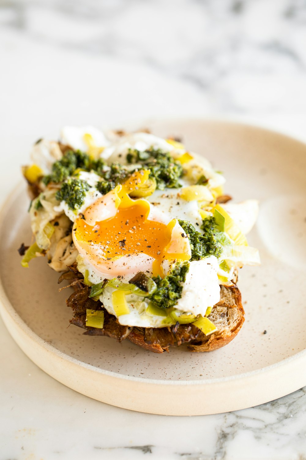 a white plate topped with an egg and broccoli sandwich