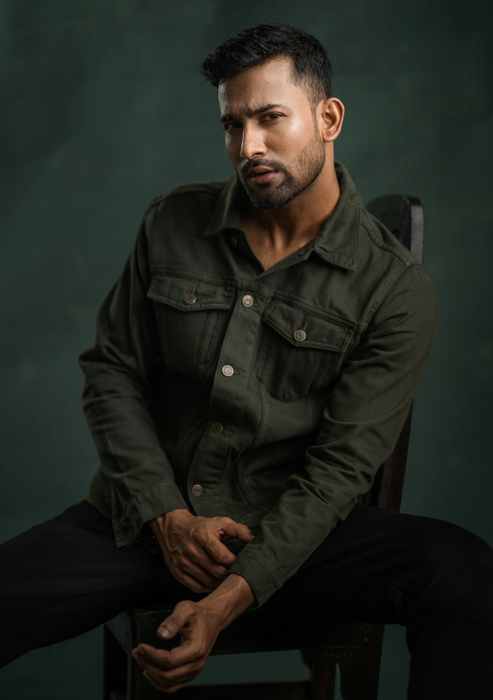 a man sitting in a chair with his hands on his knees