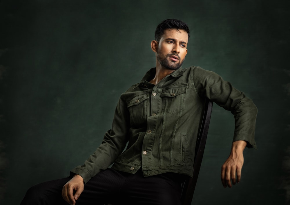 a man sitting in a chair wearing a green jacket