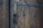 An aged wooden door with heavy, ornate metalwork and intricate patterns. The metal handle and lock show signs of wear, adding to the vintage appearance. The door is composed of vertical wooden planks with iron bolts securing them.