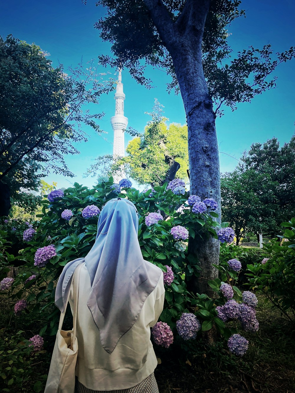 a woman in a white veil is standing in front of flowers
