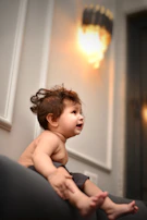 A child playing joyfully in a warm, charcoal-toned room filled with natural light.