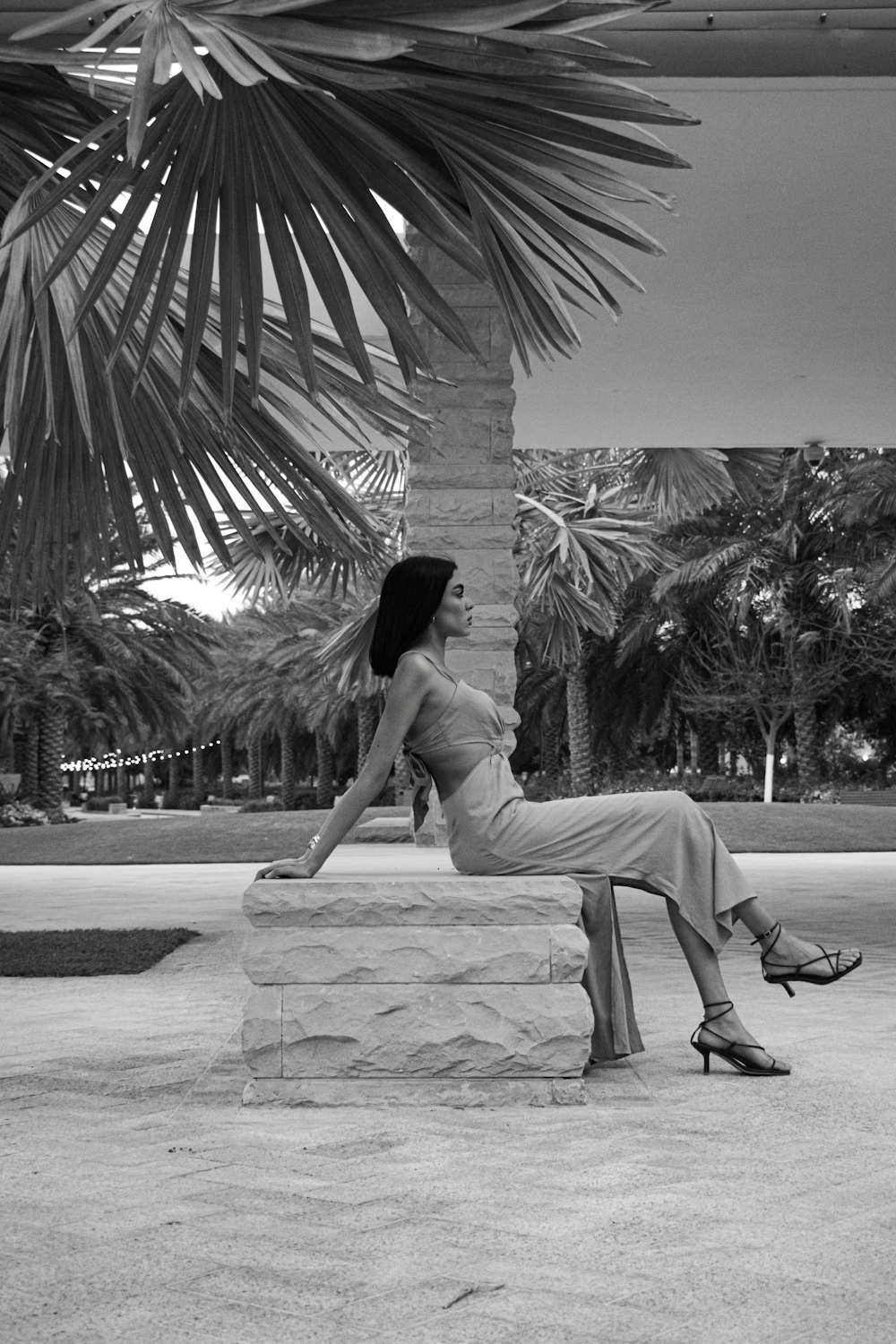 a woman sitting on top of a stone bench