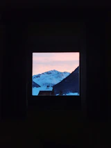 Snowy mountain view outside the restaurant window at sunset, with warm light inside.