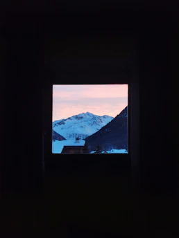 Snowy mountain view outside the restaurant window at sunset, with warm light inside.