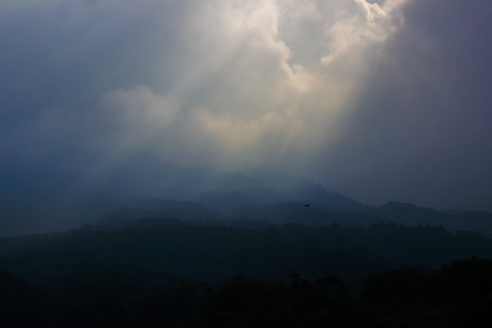 the sun shines through the clouds over the mountains