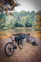 Group of friends taking a break with their bikes near a crystal-clear lake surrounded by autumn trees