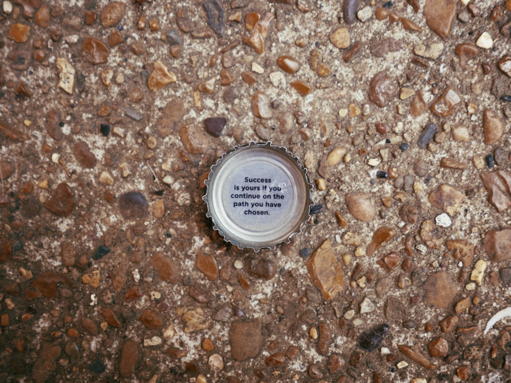 a bottle cap sitting on the ground with a quote on it
