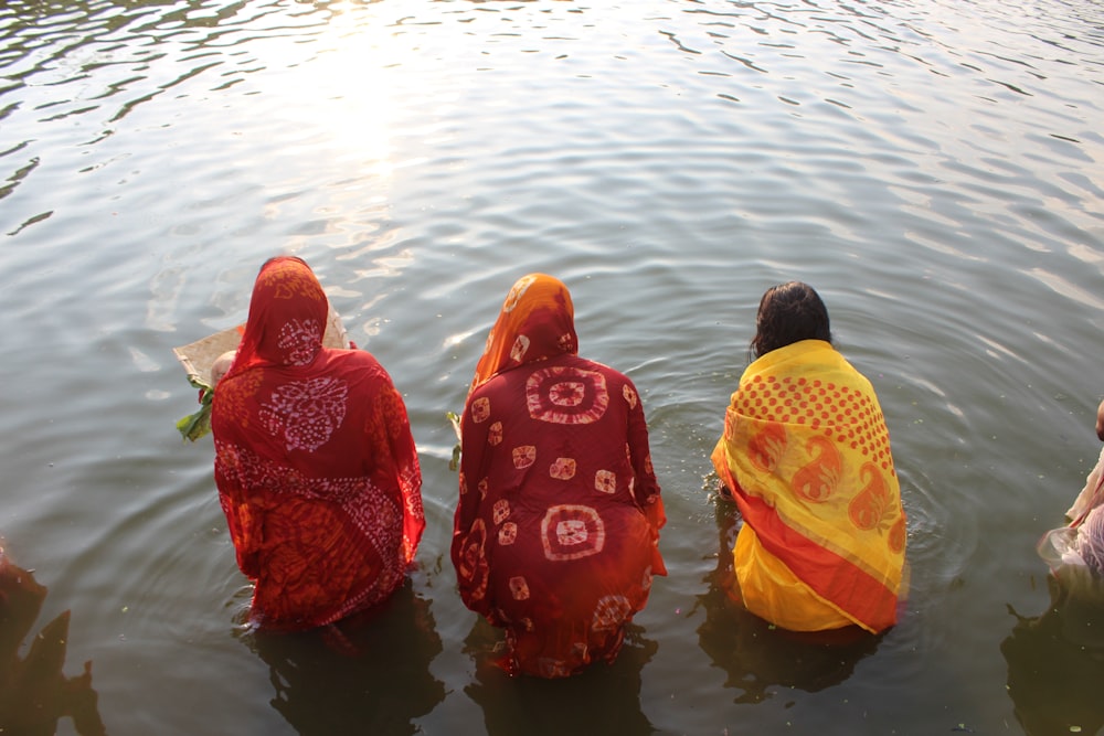 three women in sari bathing in a body of water