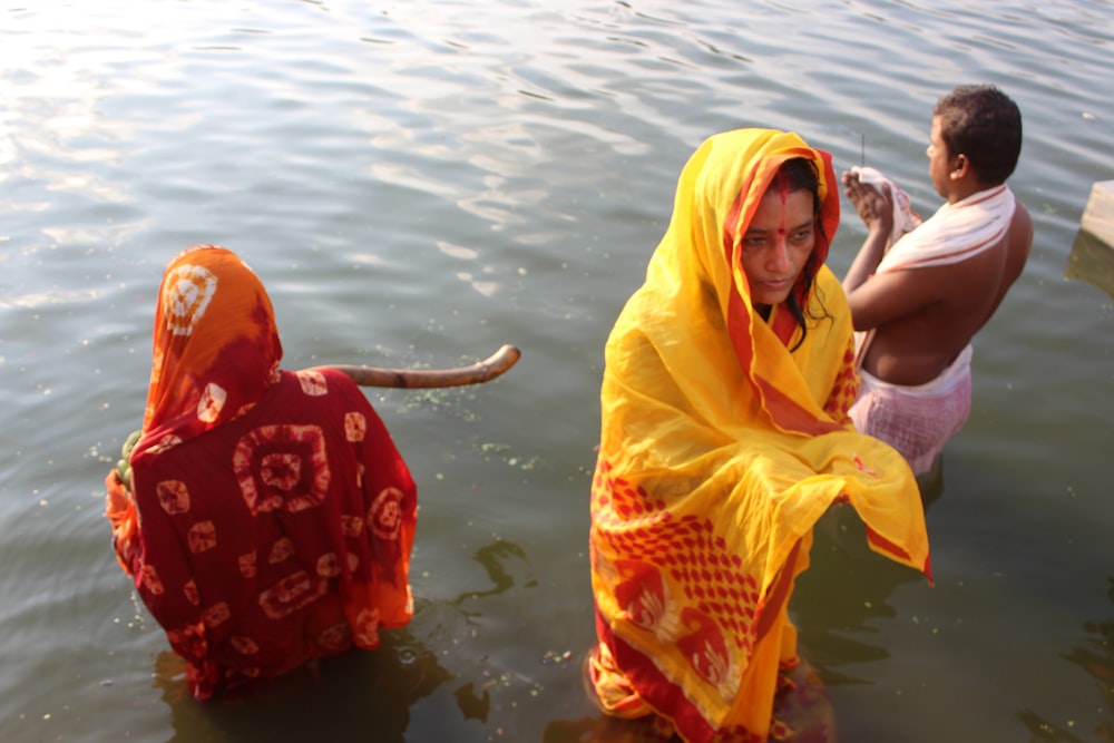 a woman in a sari standing in a body of water next to a man