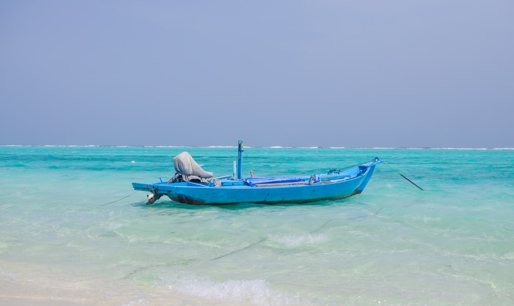 a small blue boat sitting on top of a beach