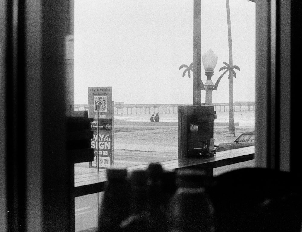 a black and white photo of a window with a view of the beach