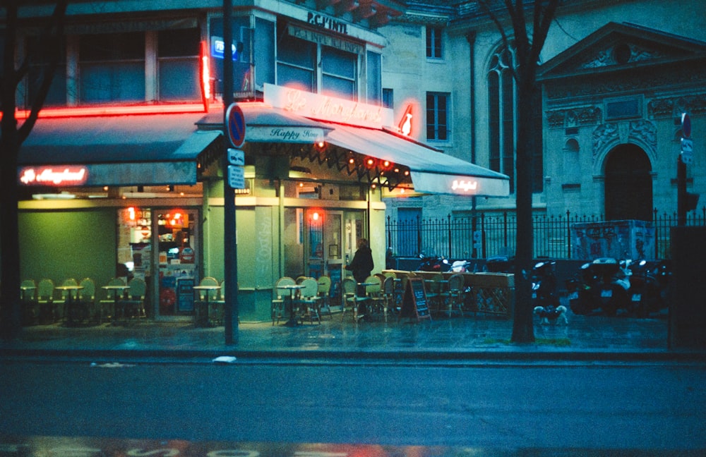 a street corner with tables and chairs on a rainy night