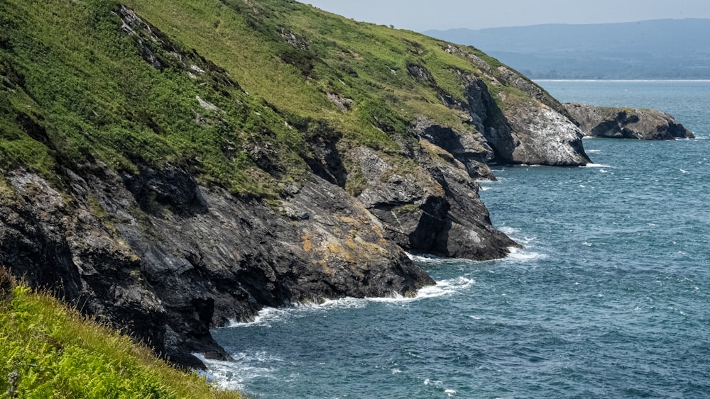 a large body of water sitting next to a lush green hillside