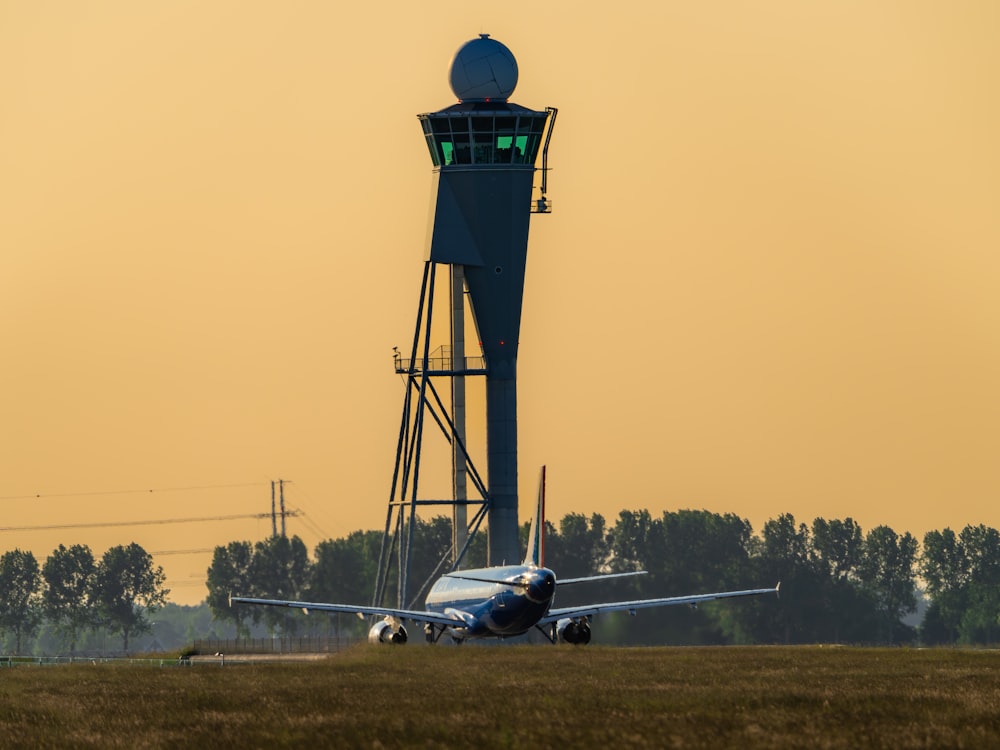 an airplane on a runway with a tower in the background