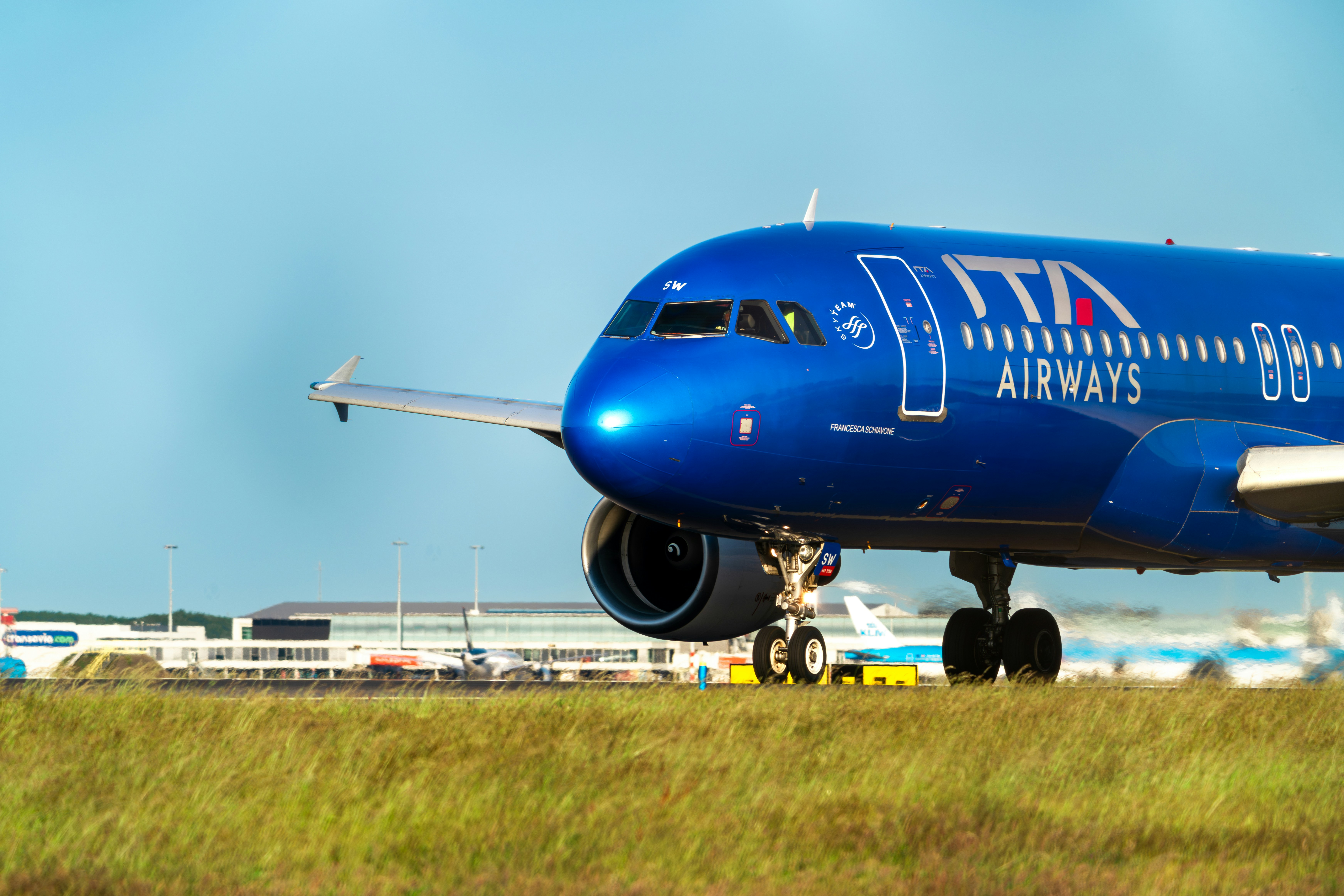 a large blue jetliner sitting on top of an airport runway, ITA Airways flight AZ113 to Milan Linate (an Airbus A320-216, reg. EI-DSW) taxiing to the Polderbaan runway at Schiphol airport for departure.