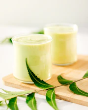 Close-up of fresh neem leaves and multani mitti powder arranged on a rustic wooden table.