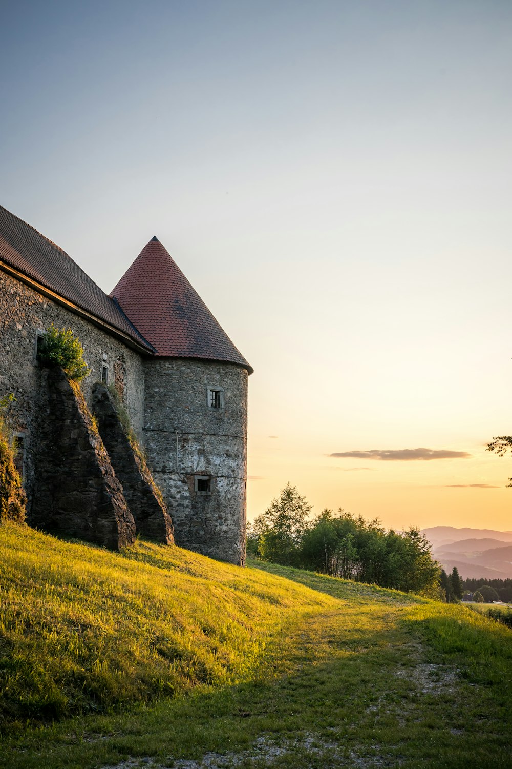 Un bâtiment en pierre assis au sommet d’une colline verdoyante