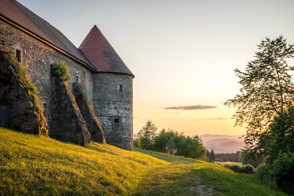 a stone building sitting on top of a lush green hillside